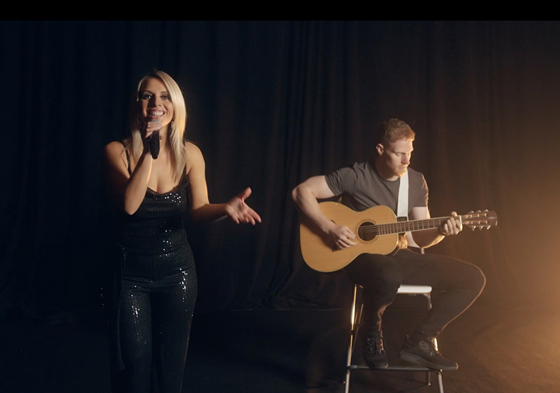 Singer and guitarist playing acoustic guitar on stool